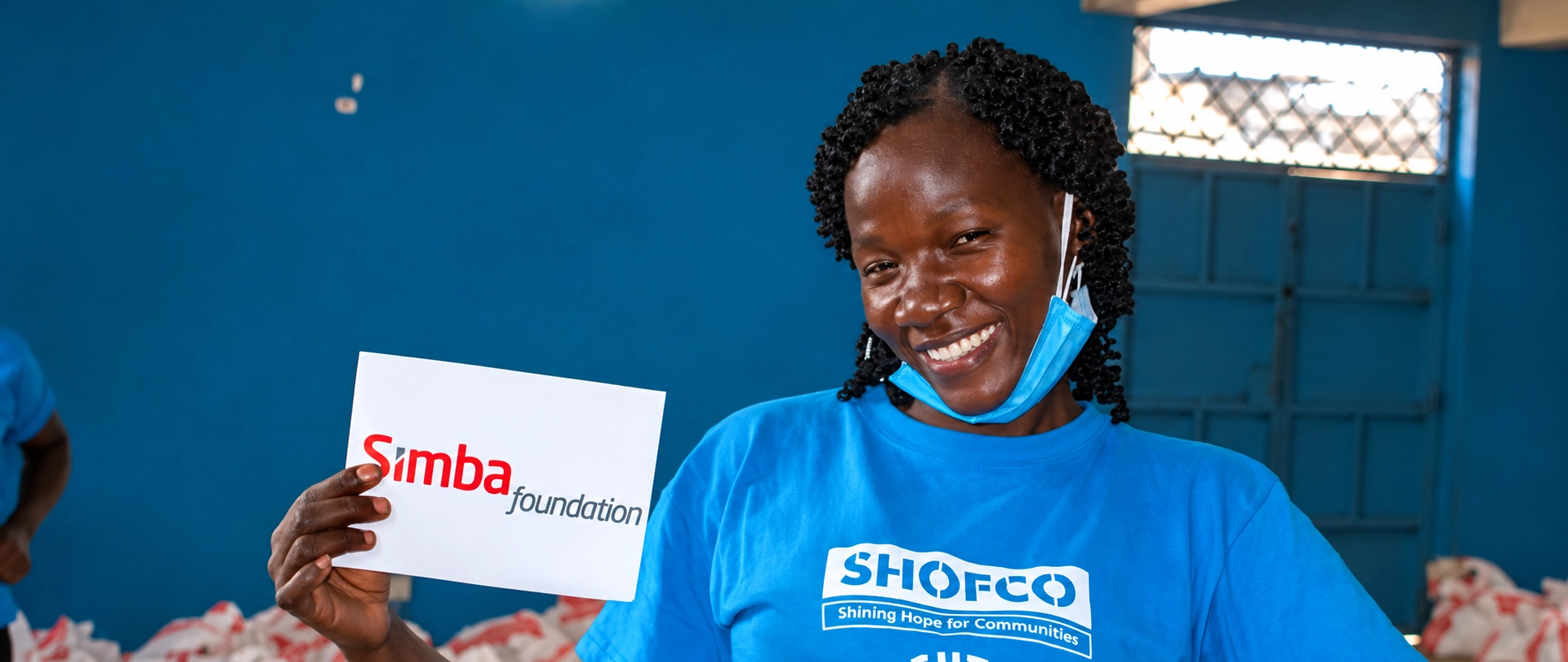 Simba Foundation volunteer holding a Foundation sign during a community programme